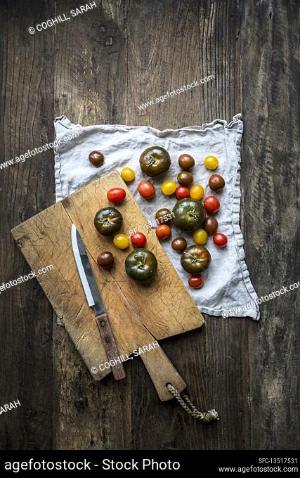 Mixed varieties of washed tomatoes on a linen tea-towel with chopping board