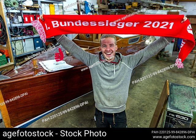 25 January 2022, Mecklenburg-Western Pomerania, Greifswald: Boat builder Florian Woll stands in the workshop of the museum shipyard with the winner's scarf as...