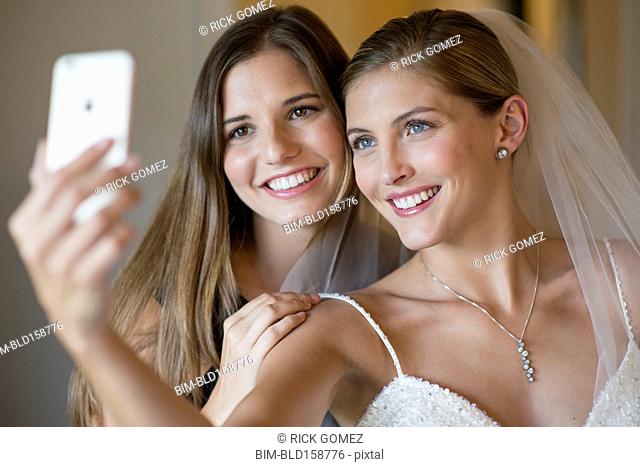 Caucasian bride and bridesmaid taking selfie