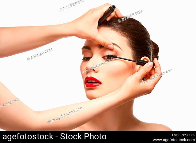 beautiful young woman applying mascara. studio beauty shot on white background. copy space
