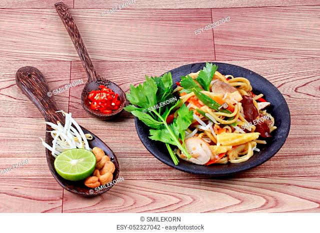 Fried sour sweet Chinese noodle with tofu, mushroom, red chili, bean sprouts, green lemon, lettuce with side dish as sliced red hot chili pepper