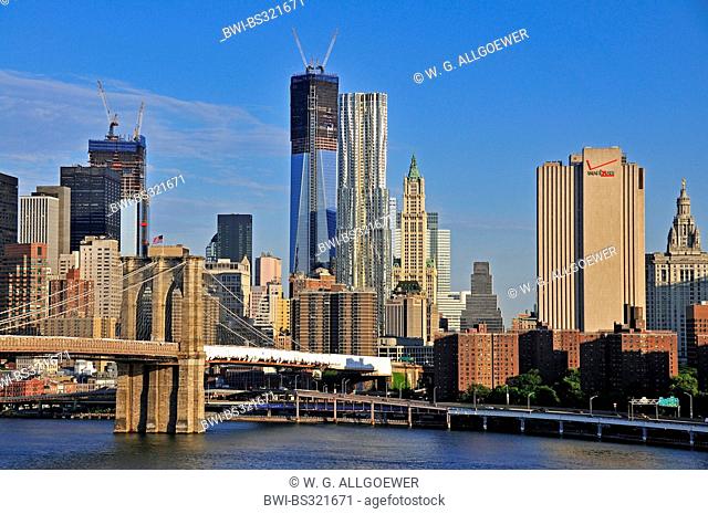 panoramic view from the Manhattan Bridge over the East River and the Brooklyn Bridge at the skyline of Lower Manhattan with the One World Trade Center which is...