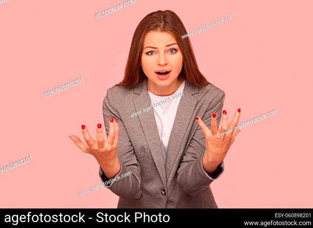 What's the problem. Portrait of irritated indignant young woman in business suit raising hands in anger and shouting why how, what do you want, quarreling