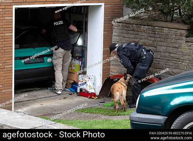 29 April 2020, North Rhine-Westphalia, Gelsenkirchen: Police investigators search in a garage of the suspect's house with a tracker dog