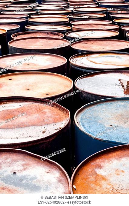 Tops of many rusted wet blue and black storage drums in rows