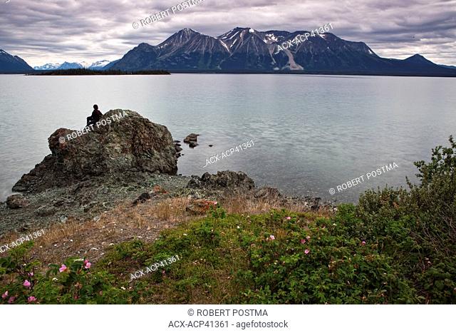 Woman sitting on rock, Atlin Lake, British Columbia, Canada