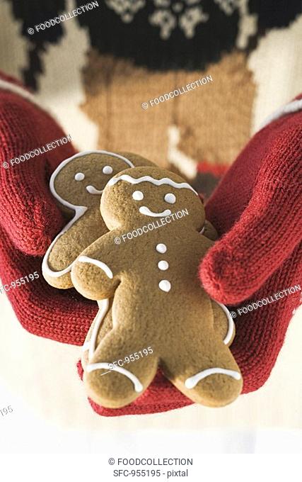 Hands in woollen gloves holding gingerbread men