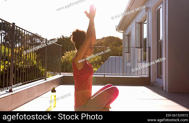 Mixed race woman exercising practicing yoga on a terrace