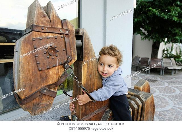 young child of two plays on a wooden horse Photographed in Austria