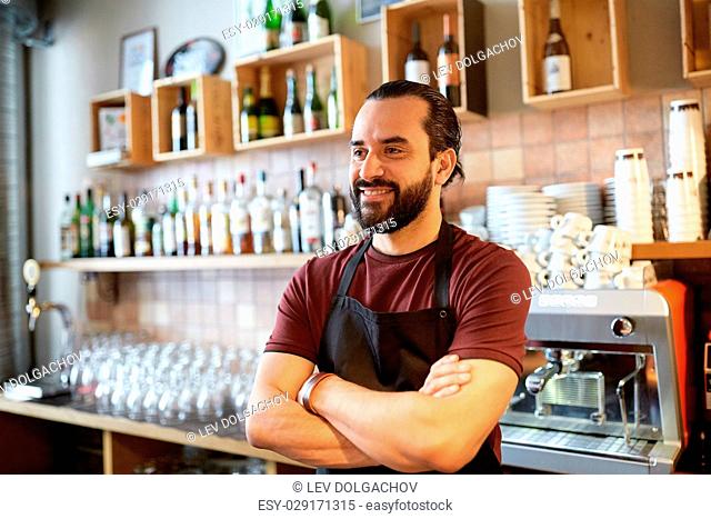 small business, people and service concept - happy man or waiter in apron at bar or coffee shop