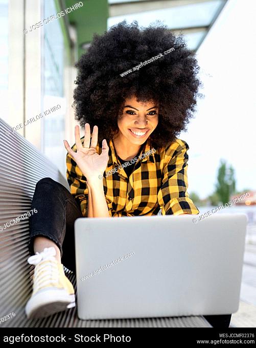 African woman waving during video call on laptop