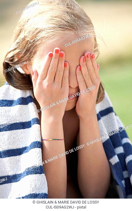 Girl wrapped in towel with her hands over her eyes