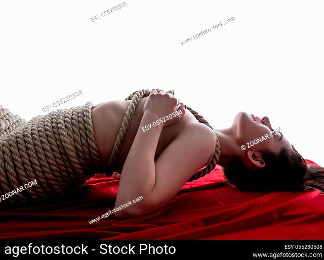 Woman tied in style of Japanese bondage. Studio photo, isolated on white backdrop