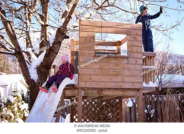 Siblings playing in snow covered playground