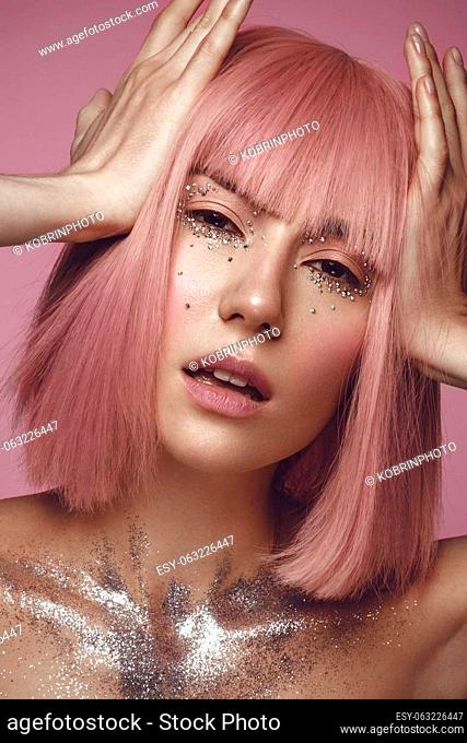 Beautiful woman in a pink wig and creative makeup with rhinestones. Beauty face. Photo taken in the studio
