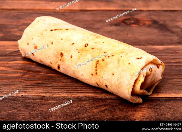 Closed shawurma rolled sandwich on a wooden background