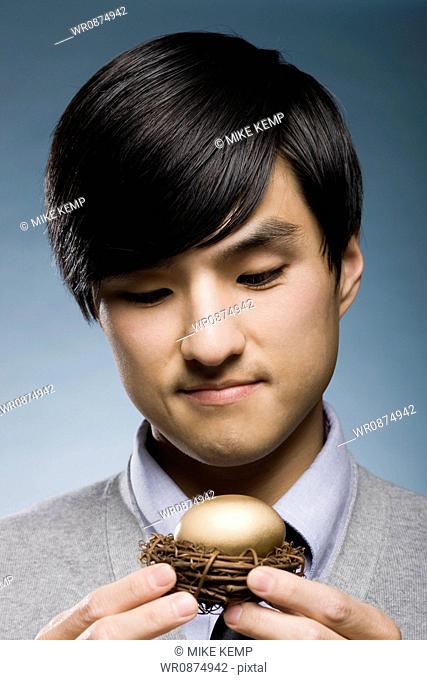 man holding a golden egg in a nest