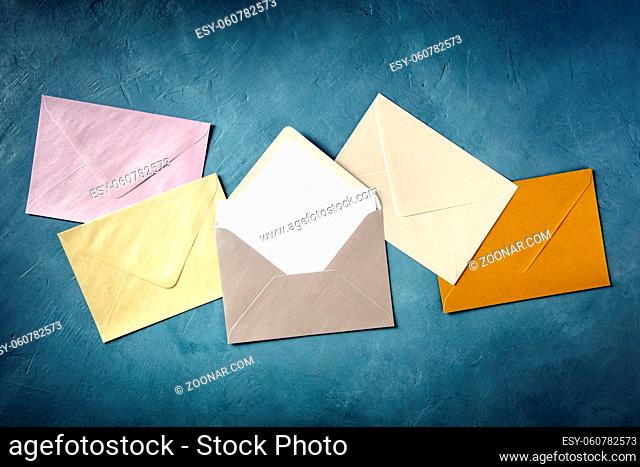 Glossy envelopes and a postcard, shot from above on a dark blue background