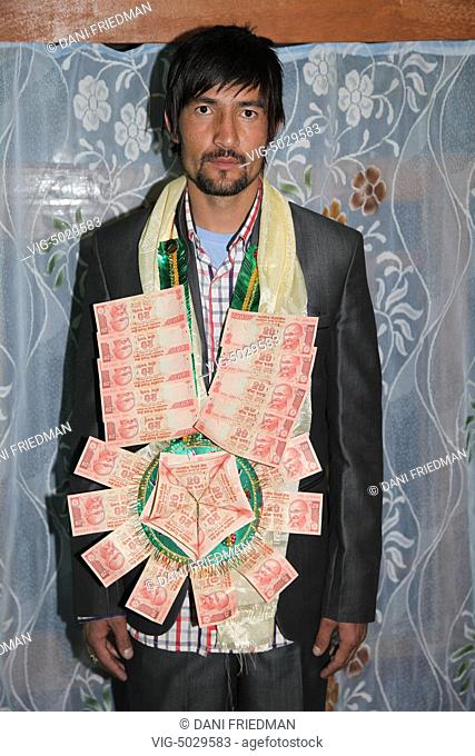 Muslim groom in traditional attire during his wedding in Kargil, Ladakh, Jammu and Kashmir, India. He is wearing a garland of money as customary in the region