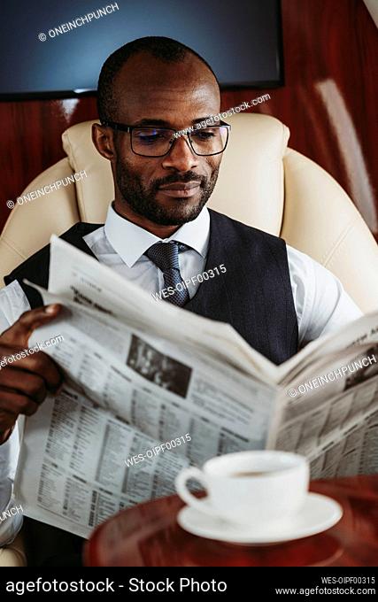 Male entrepreneur reading newspaper in airplane