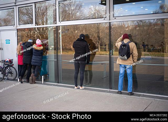Berlin, Germany, Europe - Spectators stand close to a pane of glass and watch a basketball game from outside the Max-Schmeling-Halle arena in Prenzlauer Berg in...