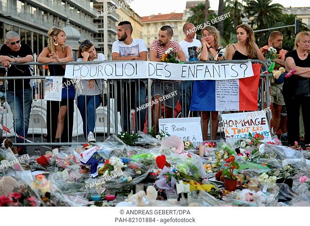 Mourners stand behind a banner reading «why children?» at the scene in Nice, France, July 16, 2016 where a truck drove into a crowd during Bastille Day...