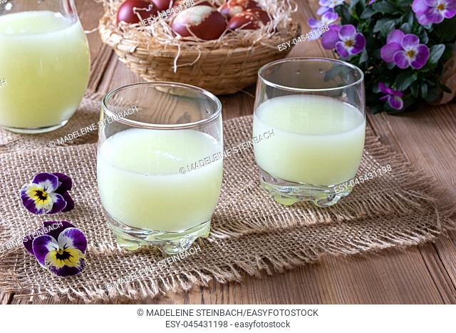 Two glasses of fresh whey with pansy flowers in the background