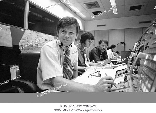 M. P. Frank (foreground), the American senior ASTP flight director, is seated at his console in the Mission Operations Control Room in the Mission Control...
