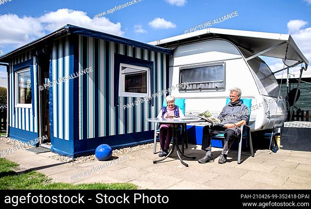 PRODUCTION - 23 April 2021, Lower Saxony, Friesoythe: Permanent campers Marianne and Paul-Jürgen Post sit in front of their caravan at the Wilken family...