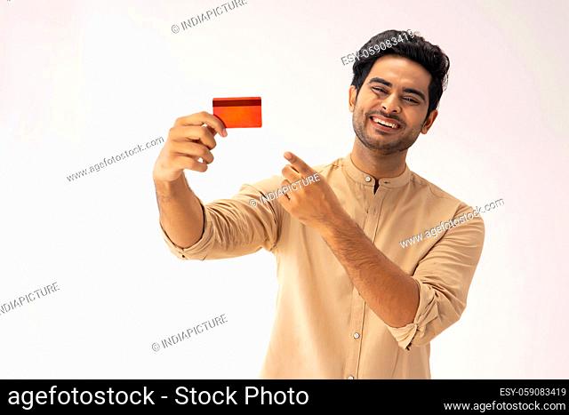 A YOUNG MAN LAUGHING AND POINTING AT DEBIT CARD
