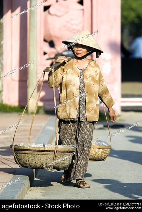 Conical hat woman with coal in shoulder basket landmark Japanese Covered Bridge Hoi An Vietnam