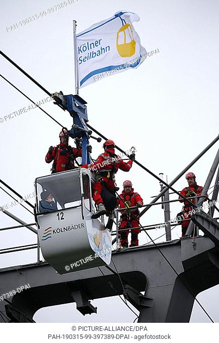 15 March 2019, North Rhine-Westphalia, Köln: Fire brigade height rescuers climb onto a gondola during an exercise on the cable car across the Rhine