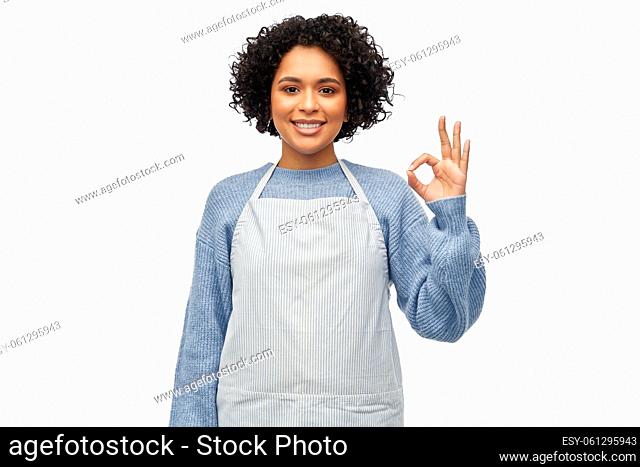 smiling woman in apron showing ok gesture