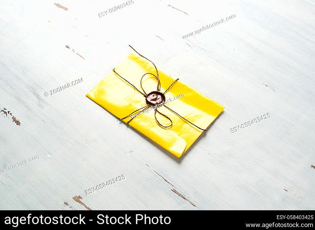 Yellow letter envelope with wax seal on wooden surface