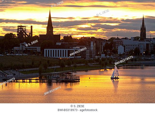 sailing boats on Lake Phoenix with the silhouette of the district Hoerde at sunset, Germany, North Rhine-Westphalia, Ruhr Area, Dortmund