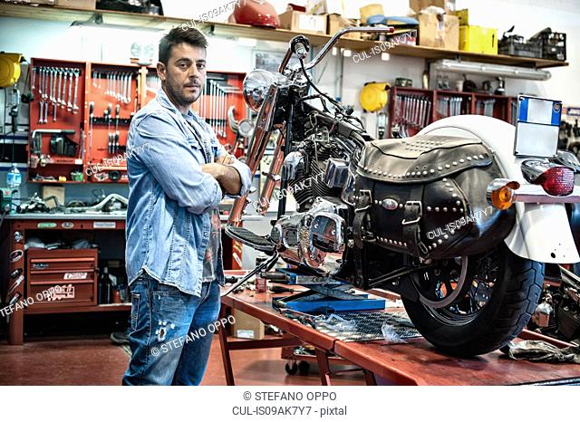 Portrait of male mechanic with arms crossed in motorcycle workshop
