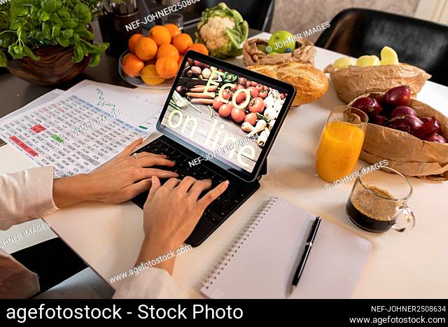 Person's hands using laptop in kitchen