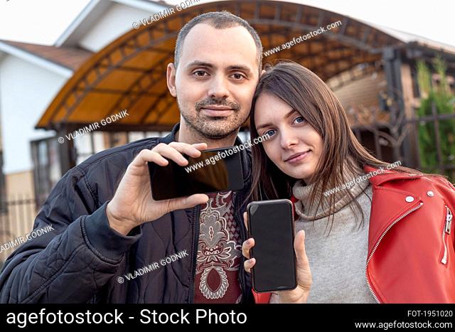 Portrait young couple with camera phones