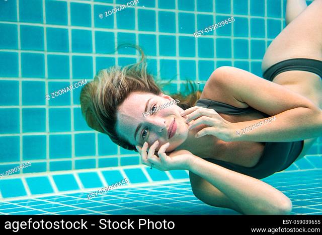Beautiful woman with long red hair posing underwater in bikini