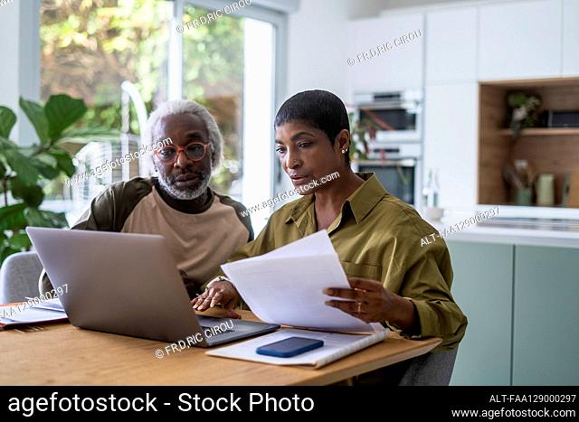 Couple checking documents in kitchen