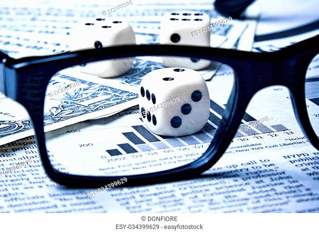 dice on financial chart near dollars seen by unfocused glasses
