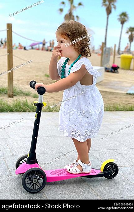 Little girl, playing with her scooter in the street