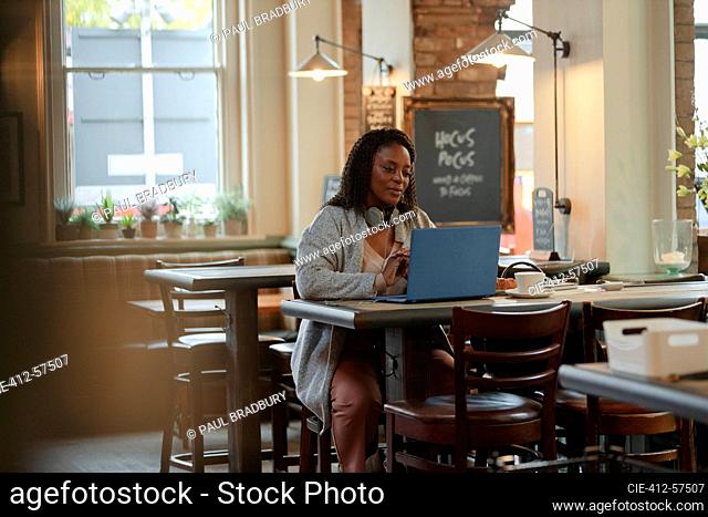 Woman working at laptop at cafe table