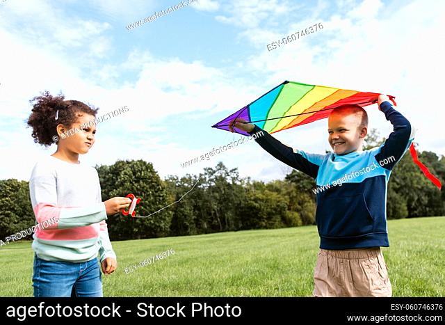happy boy and girl with kite playing at park