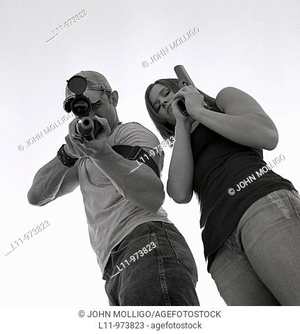 Man and women with guns; aiming at lens