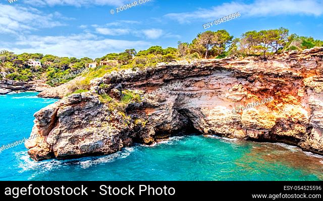 Houses on cliffs around beautiful beach, Cala Llombards in Mallorca, turquoise water and blue sky, Balearic Island, Spain