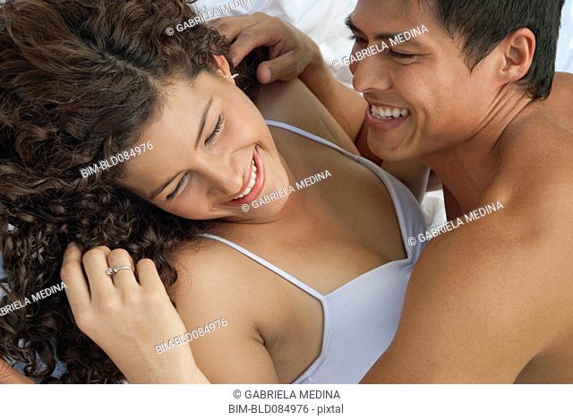 Laughing Hispanic couple laying in bed