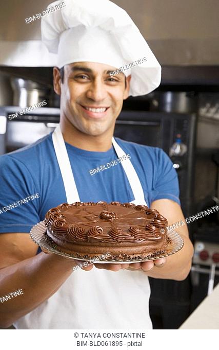 Hispanic male pastry chef holding cake