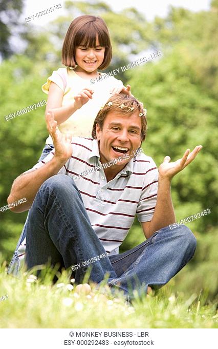 Father and daughter sitting outdoors with flowers smiling