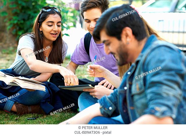 Male and female students sitting chatting and working on college campus
